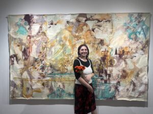 Ashley Frost poses in front of painting.